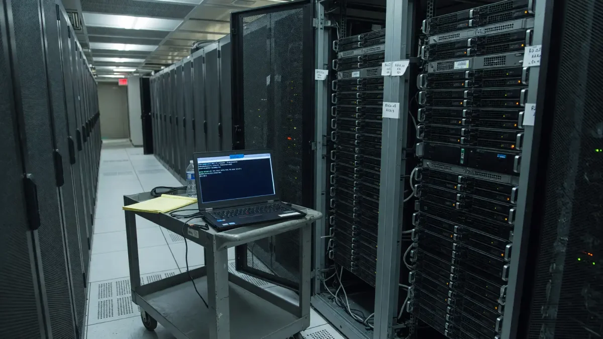 Rack server with a laptop showing a terminal kernel version string, cool aisle lighting, no logos.